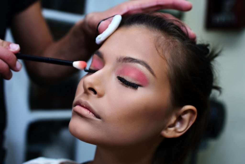 woman with pink lipstick holding white and purple toothbrush